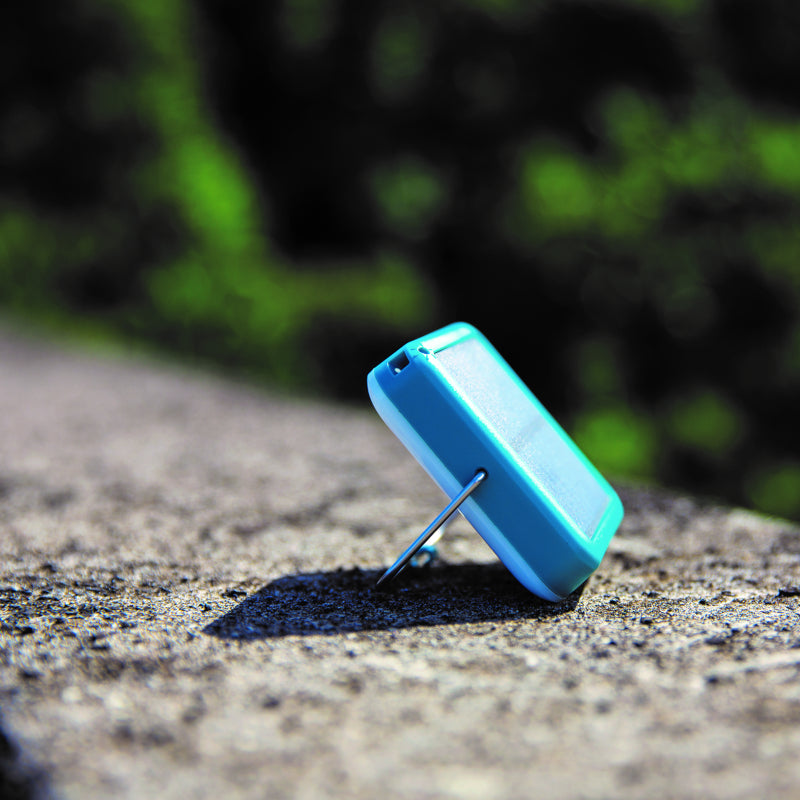 Teal coloured BioLite SunLight 100 shown resting on it's kickstand in the sun.